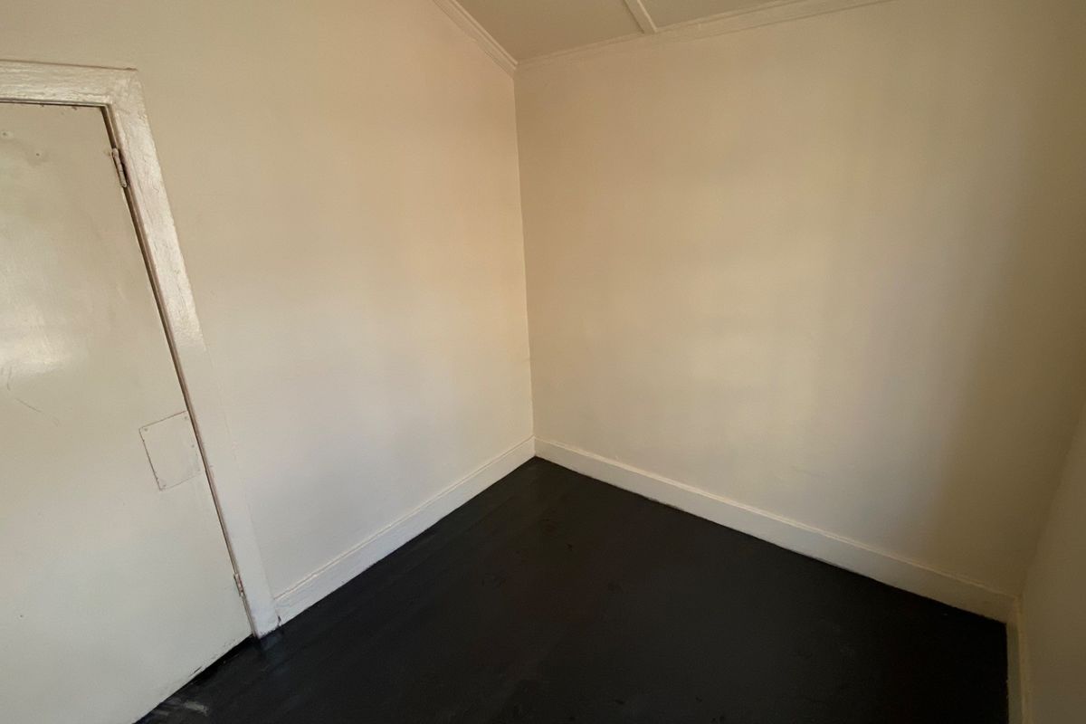 An empty bedroom featuring dark painted timber flooring and neutral wall tones, providing a blank canvas for potential interior design updates.