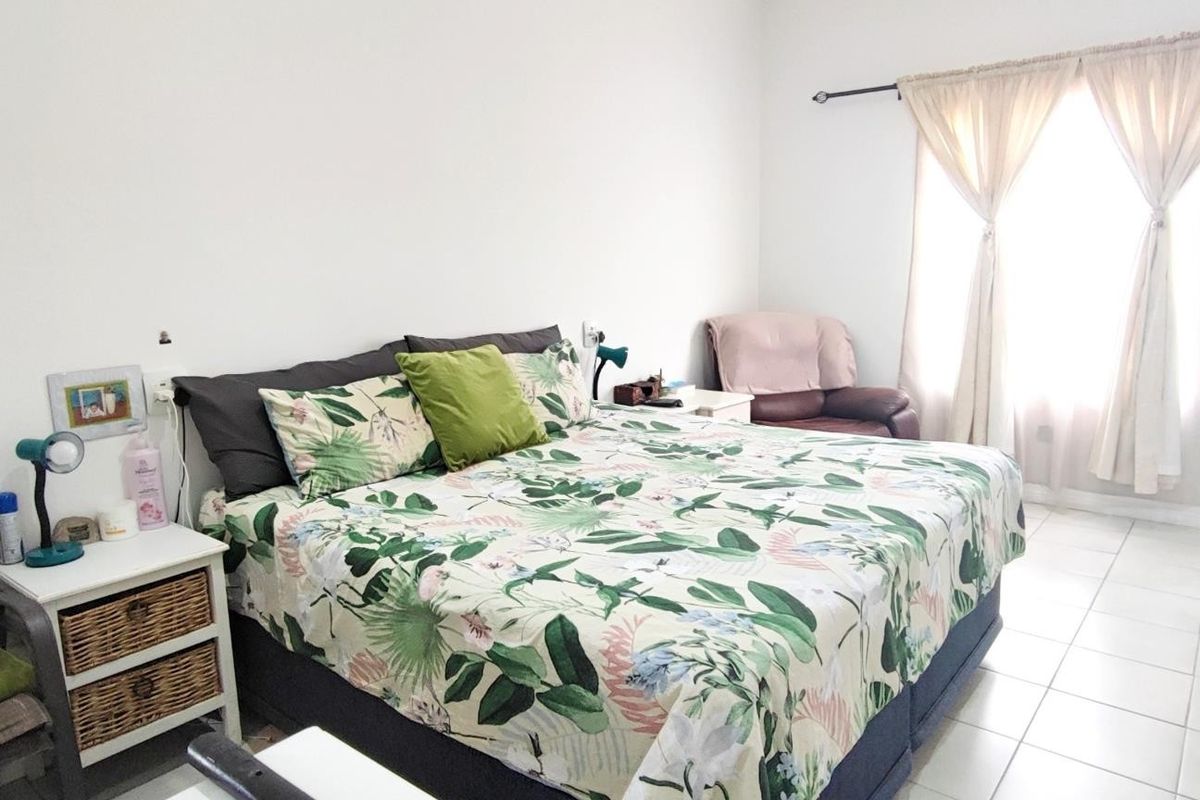 A bedroom featuring tiled flooring and a window with a curtain rod, providing a functional and neutral space.