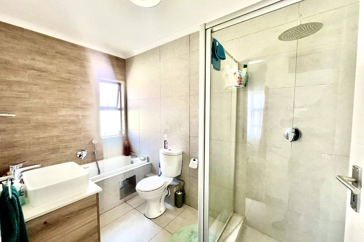 Modern bathroom featuring a glass-enclosed walk-in shower, a separate bathtub, a vanity unit, and neutral wall and floor tiling.