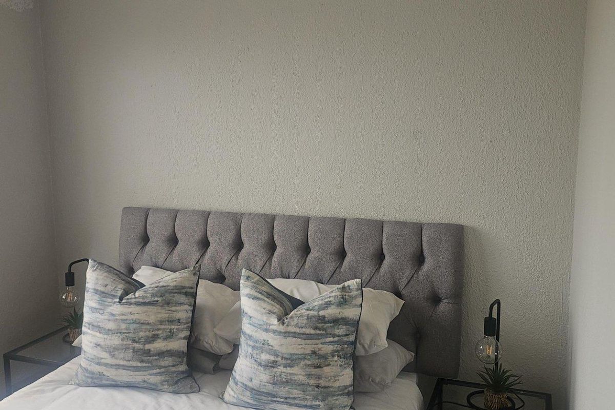 A bedroom featuring a neutral wall finish and a window with fitted blinds, providing natural light.