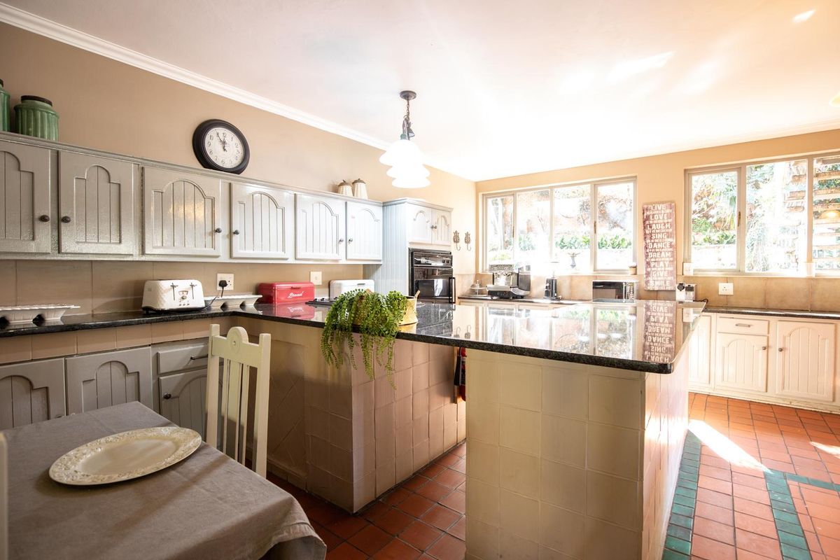 Spacious kitchen featuring a large central island with granite countertops, ample cabinetry, and tiled flooring, offering a functional layout for food preparation.