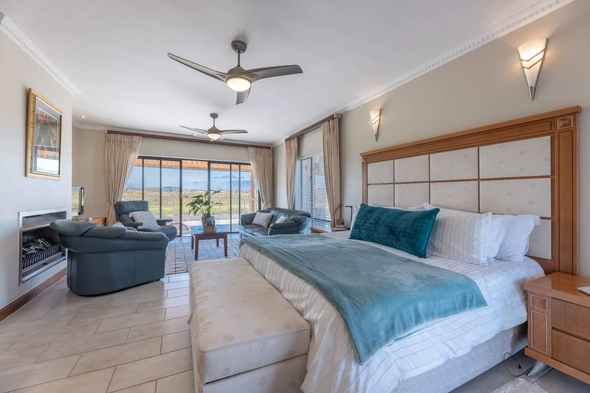 Spacious bedroom featuring a built-in fireplace, tiled flooring, ceiling fans, and large sliding glass doors opening to a scenic outdoor view.