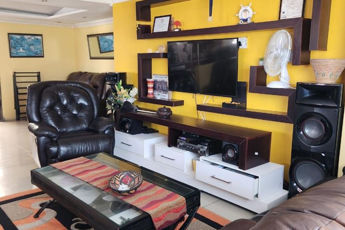 Spacious living room featuring a prominent built-in wall shelving unit, decorative ceiling cornices, and recessed lighting.