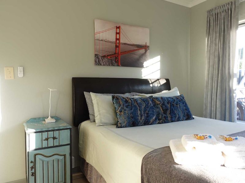 A well-lit bedroom featuring neutral wall tones, window treatments, and functional electrical fixtures.