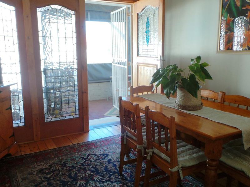 Dining room featuring timber flooring and decorative leaded glass double doors providing access to an outdoor patio area.
