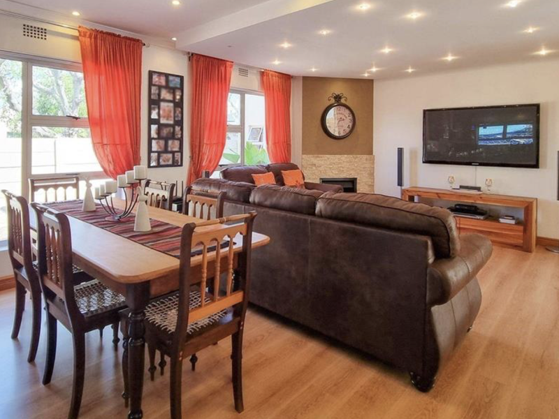Spacious open-plan living and dining area featuring laminate flooring, recessed lighting, and a feature fireplace with stone cladding.
