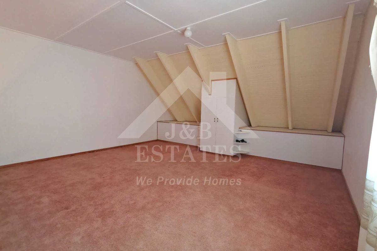 An attic-style bedroom featuring sloped ceilings, built-in storage cabinetry, and carpeted flooring.