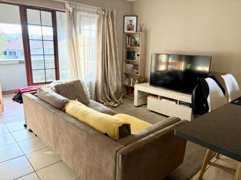A comfortable living room featuring tiled flooring and a large sliding glass door providing direct access to an outdoor balcony area.