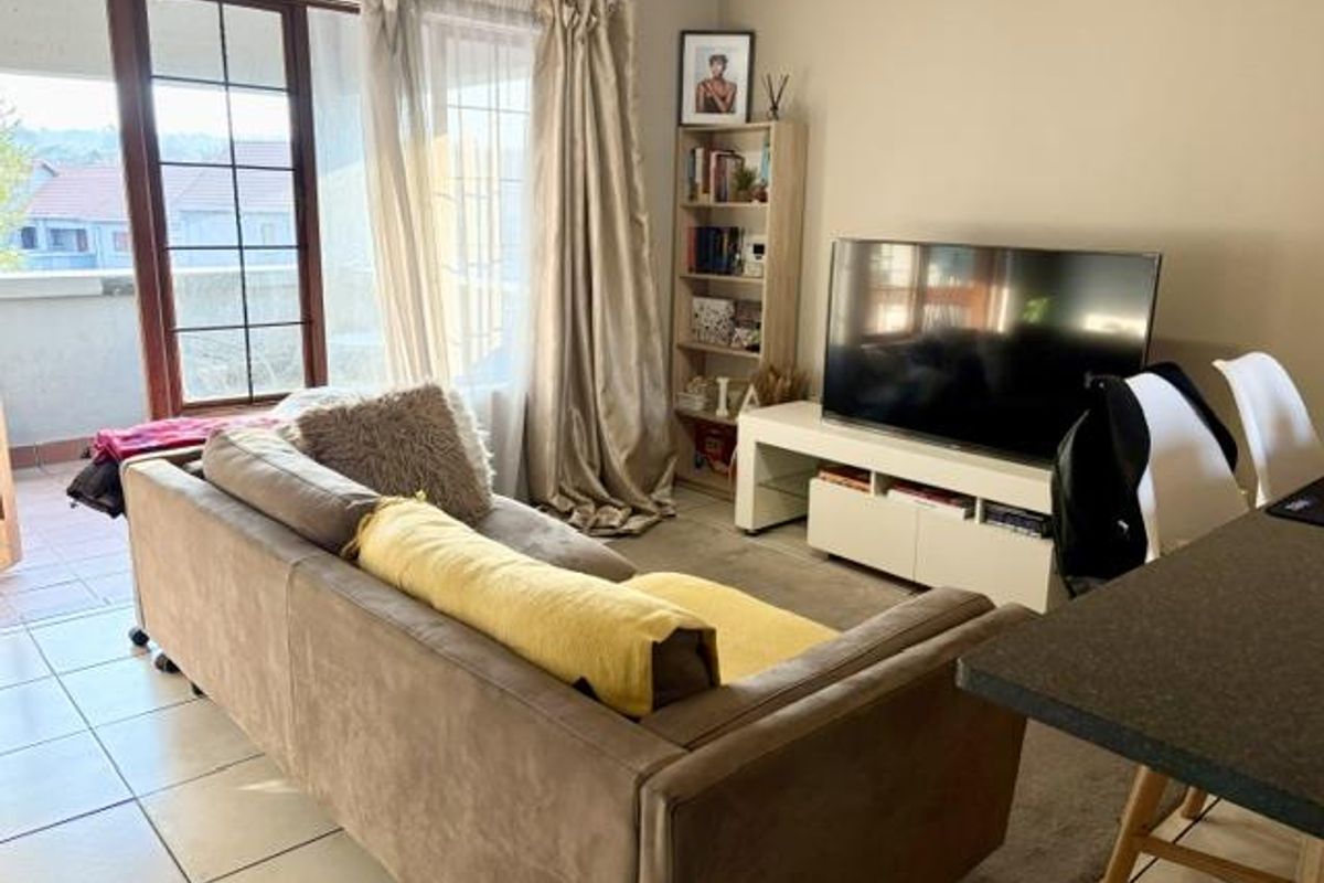 A comfortable living room featuring tiled flooring and a large sliding glass door providing direct access to an outdoor balcony area.