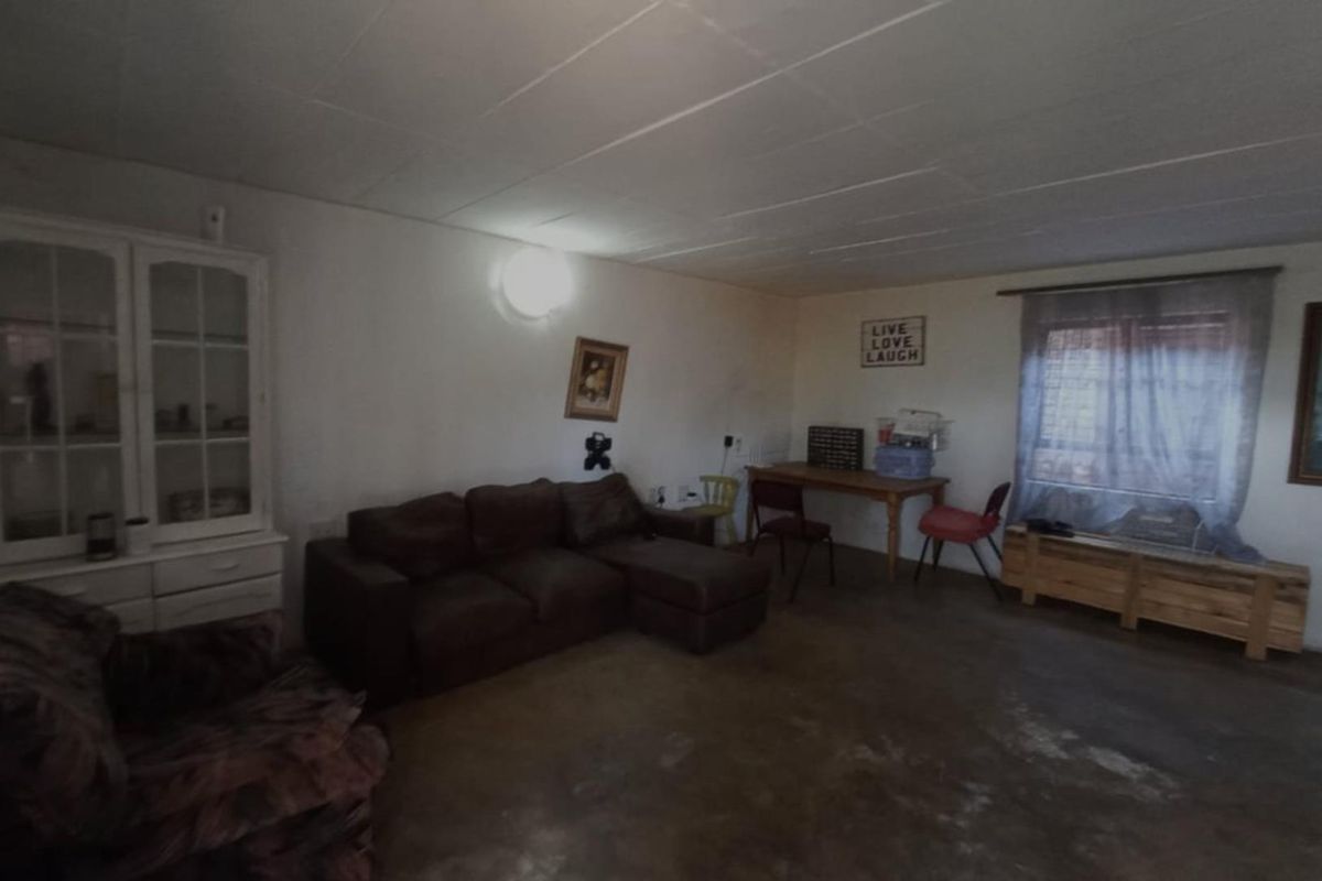 Spacious living area featuring concrete flooring and a tiled ceiling, offering a blank canvas for renovation and interior design updates.