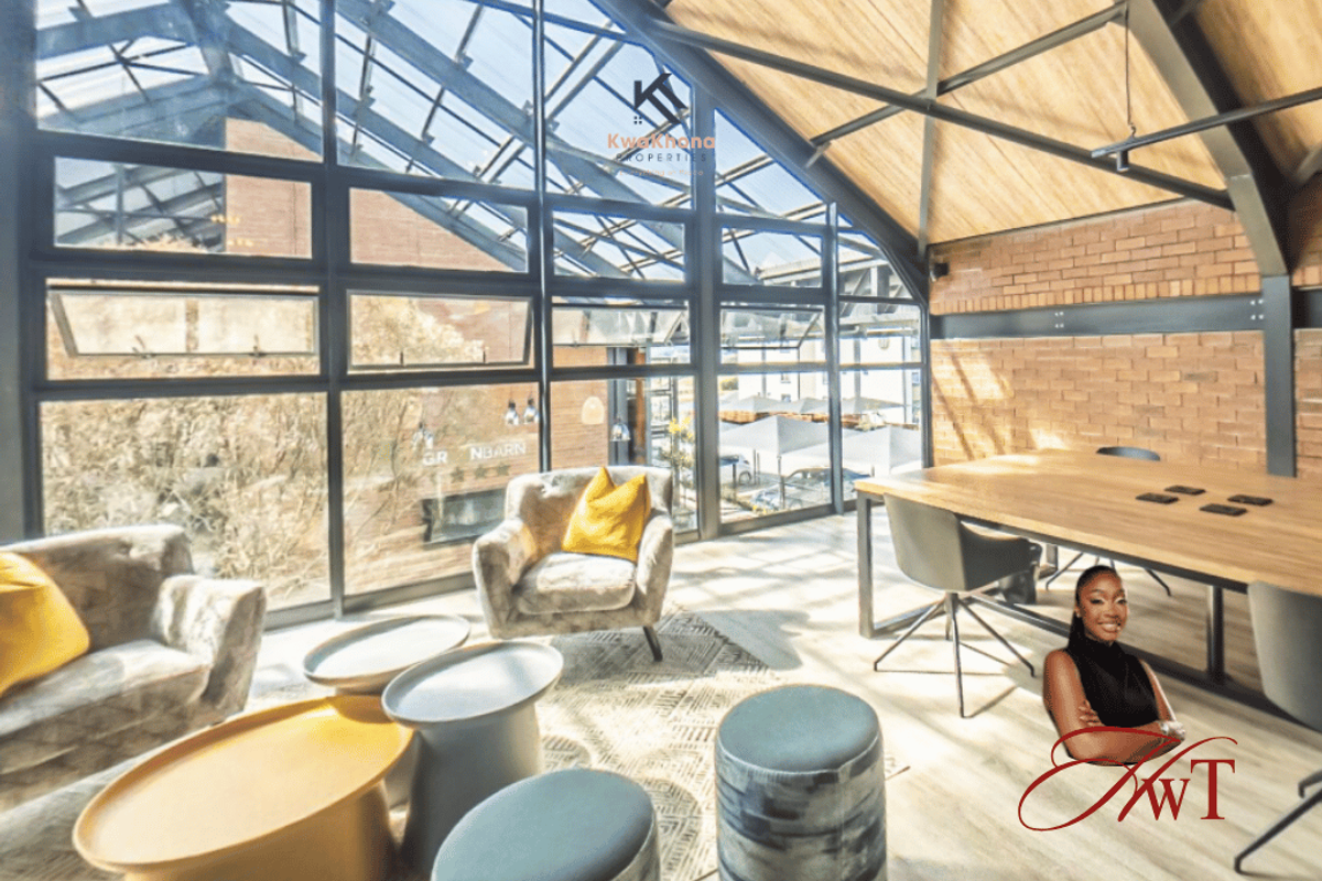 Spacious living area featuring industrial-style architecture with exposed brick walls, steel roof trusses, and expansive windows providing ample natural light.