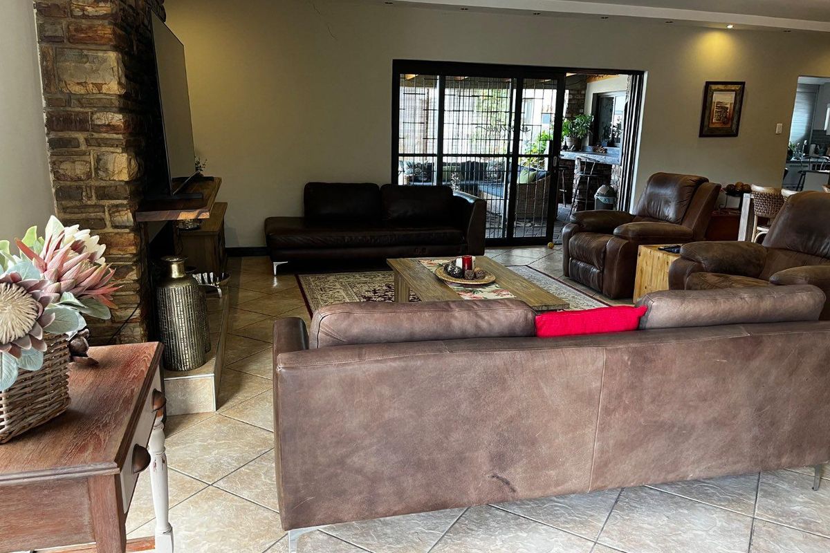 Spacious living area featuring a prominent stone-clad fireplace, tiled flooring, and large sliding doors providing seamless access to the outdoor patio.
