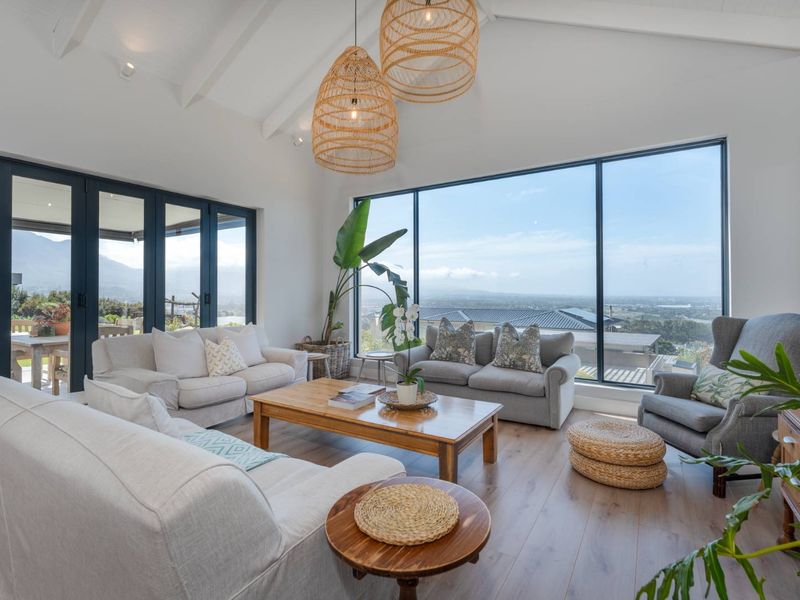 Spacious living room featuring a vaulted ceiling with exposed rafters, large floor-to-ceiling windows, and bi-fold doors opening to an outdoor area with scenic views.