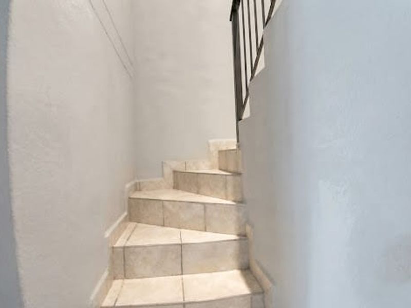 A staircase featuring tiled steps and a metal balustrade, providing access between levels within the townhouse.