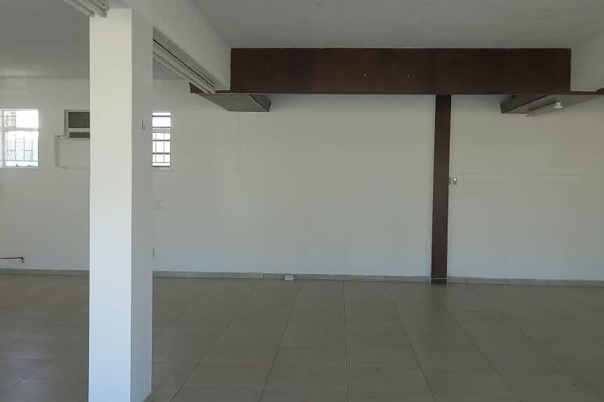Spacious open-plan retail area featuring tiled flooring, structural support columns, and exposed beams, providing a versatile blank canvas for various business layouts.