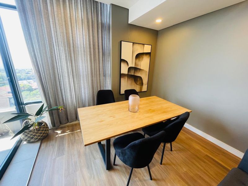 A modern dining area featuring floor-to-ceiling windows that provide ample natural light and views, complemented by sleek laminate flooring and recessed ceiling lighting.