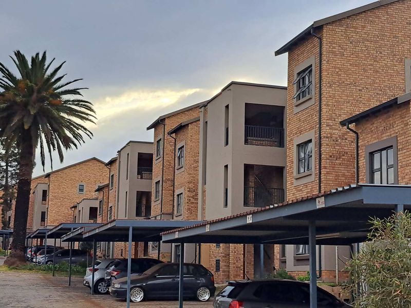 Exterior view of a multi-story apartment complex featuring face brick architecture and dedicated covered parking bays for residents.