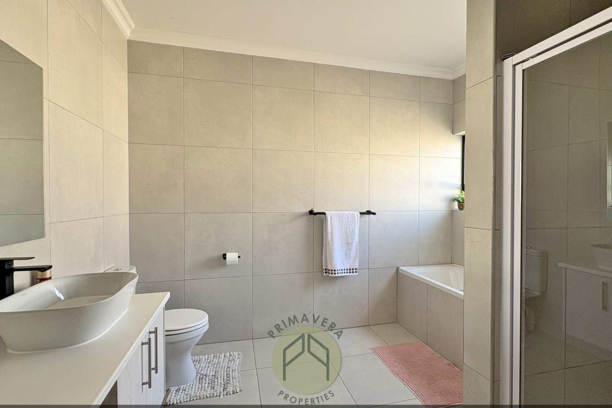 Modern bathroom featuring a vessel sink on a vanity cabinet, a built-in bathtub, and a separate shower enclosure with neutral wall and floor tiling.