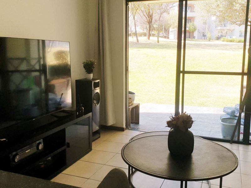Living room featuring tiled flooring and a large sliding glass door providing direct access to the outdoor garden area.