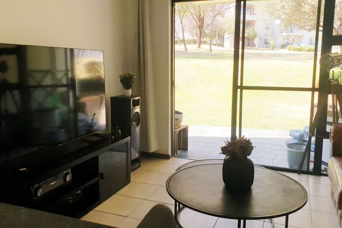 Living room featuring tiled flooring and a large sliding glass door providing direct access to the outdoor garden area.