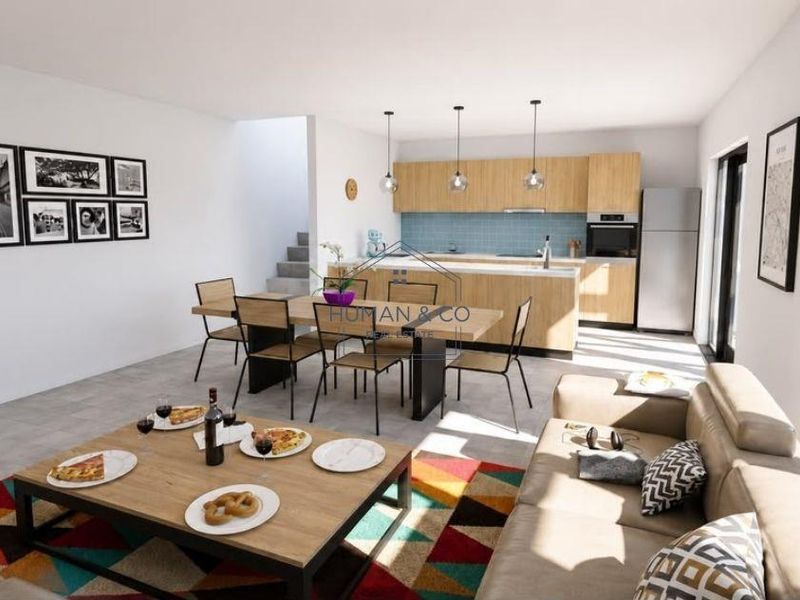 Modern open-plan living and dining area featuring a contemporary kitchen with light wood cabinetry, tiled backsplash, and integrated appliances.