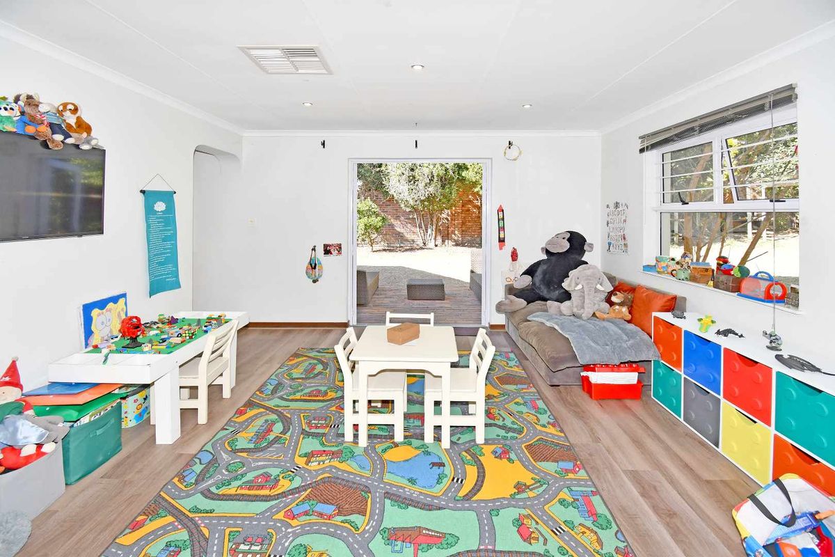 A bright, versatile living area featuring laminate flooring, recessed lighting, and direct access to the rear patio through a sliding glass door.