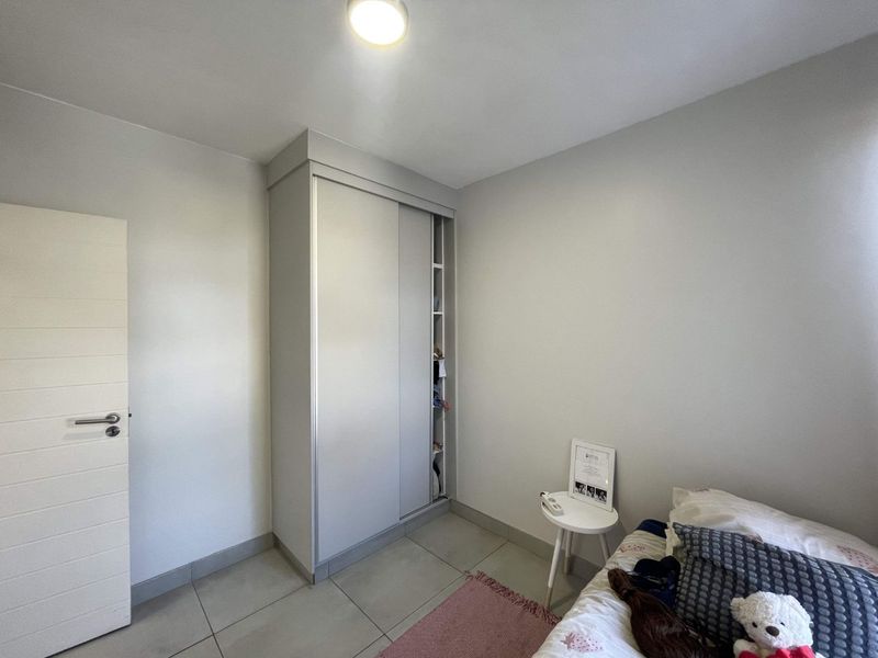 A bedroom featuring neutral tiled flooring and a modern built-in sliding door wardrobe.