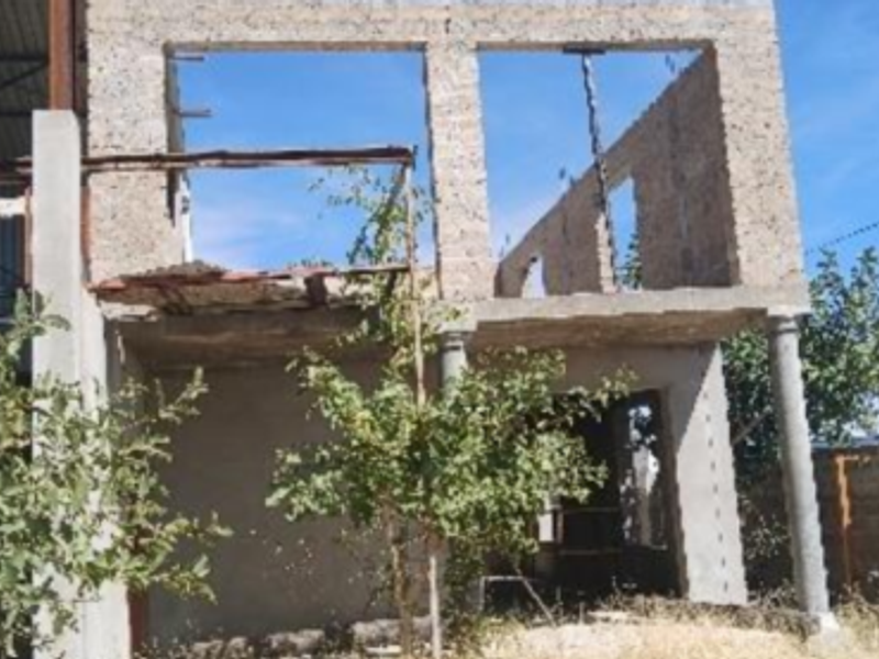 An unfinished two-story industrial or commercial structure showing exposed concrete block walls, steel framing, and open window apertures in a shell state.