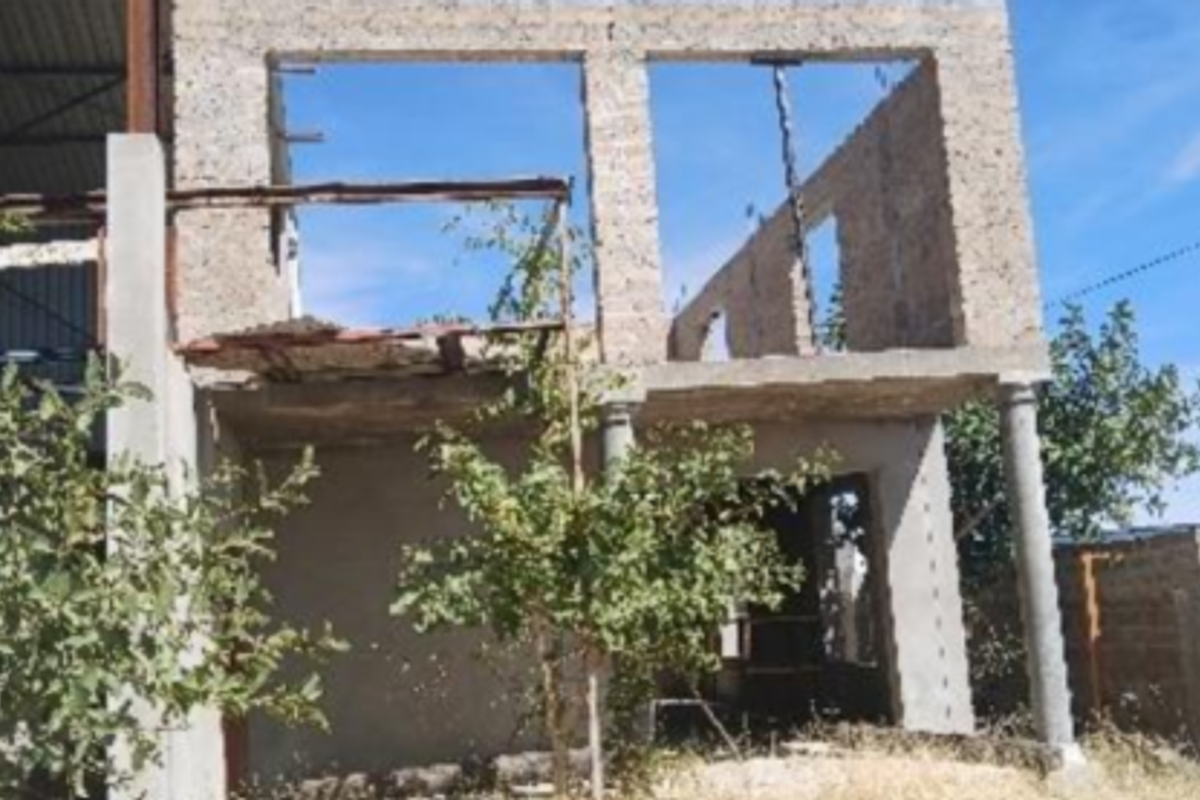 An unfinished two-story industrial or commercial structure showing exposed concrete block walls, steel framing, and open window apertures in a shell state.