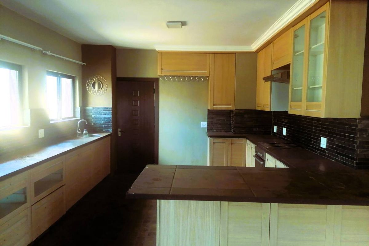A spacious kitchen featuring light wood cabinetry, dark tiled countertops, and a tiled backsplash, offering a functional layout ready for modern updates.