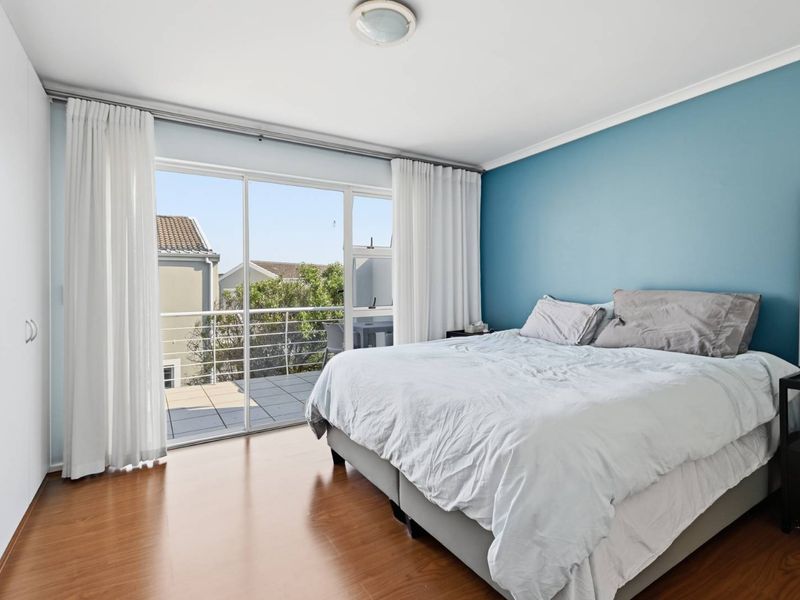 Bright bedroom featuring laminate flooring, a built-in wardrobe, and large sliding glass doors providing direct access to a private balcony.