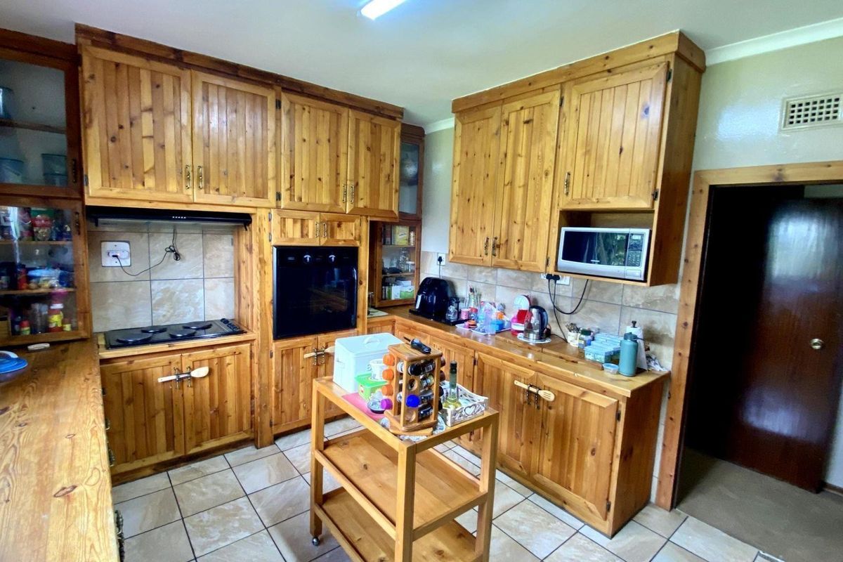 A traditional kitchen featuring extensive solid wood cabinetry, built-in oven, hob, extractor fan, and tiled flooring.