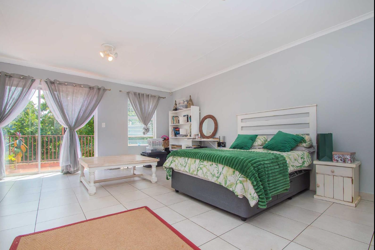 Spacious bedroom featuring tiled flooring, neutral wall tones, and a sliding glass door providing access to an outdoor balcony area.