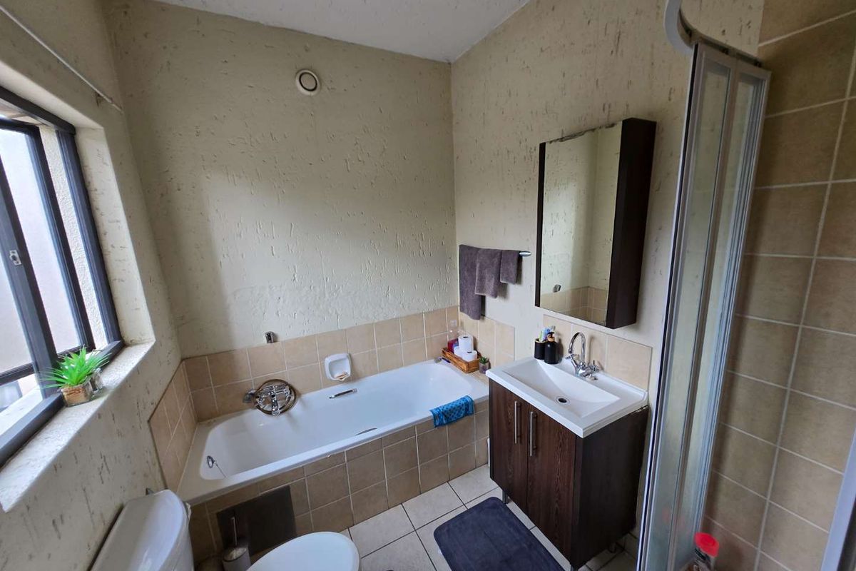 Functional bathroom featuring a built-in bathtub, vanity cabinet with integrated sink, and a separate shower enclosure with tiled surrounds.
