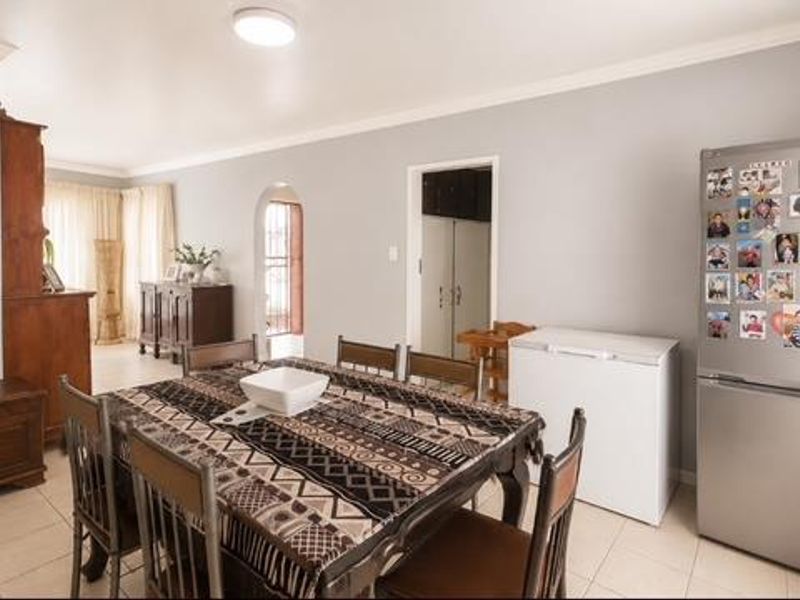 A spacious dining area featuring neutral walls, tiled flooring, and a classic archway leading to adjacent living spaces.