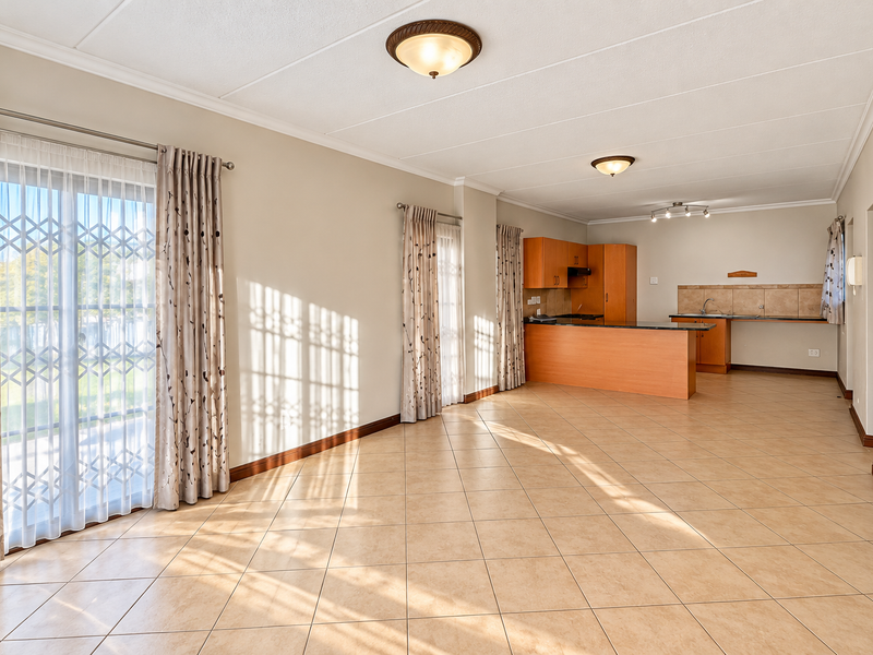 Spacious open-plan living and kitchen area featuring tiled flooring, built-in cabinetry, and large sliding doors providing access to the exterior.