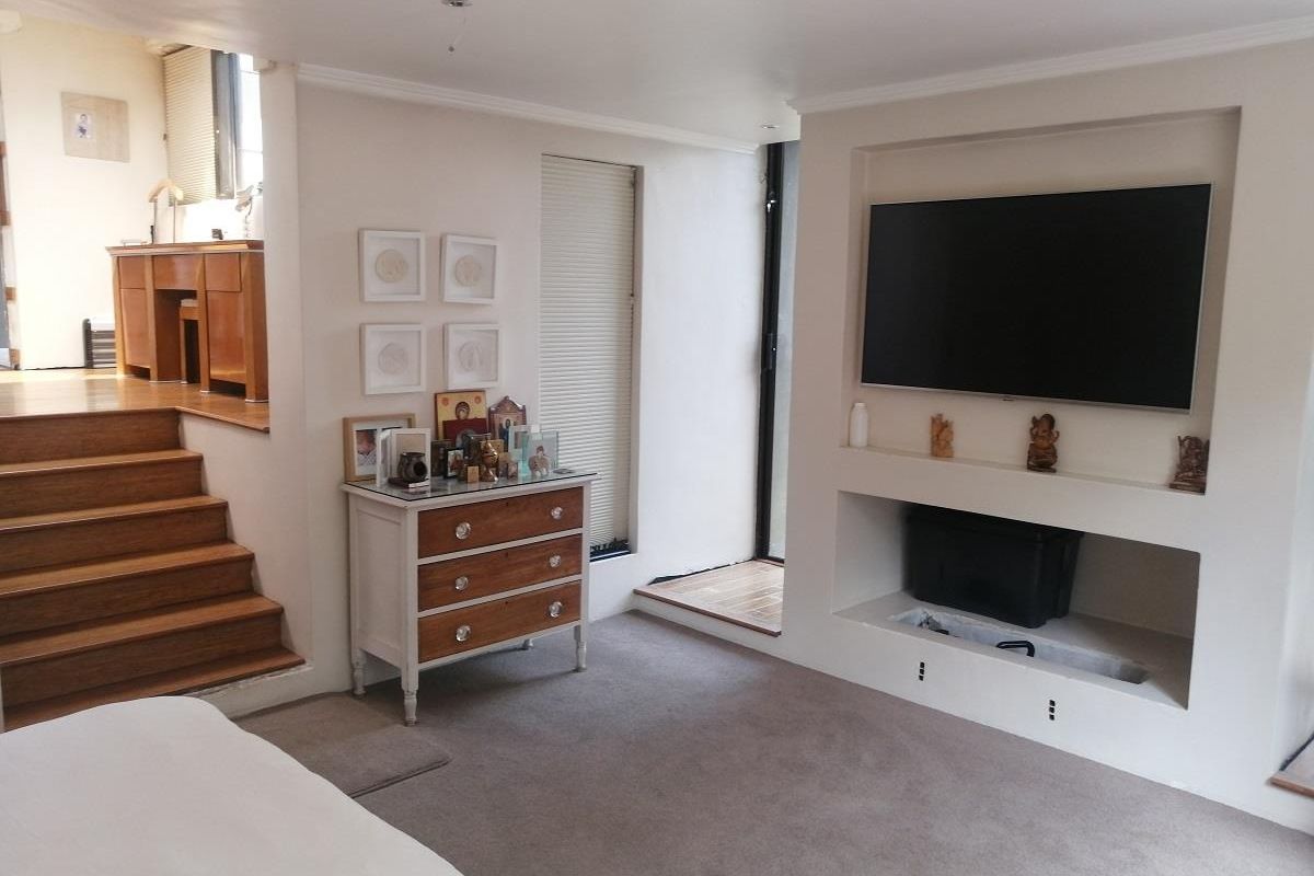 Living room featuring a built-in media wall with fireplace cavity, carpeted flooring, and steps leading to an elevated study or transition area.