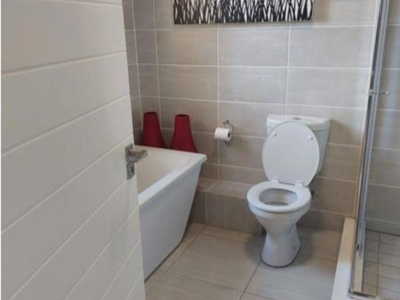 Modern bathroom featuring a freestanding bathtub, separate shower enclosure, and neutral ceramic tiling throughout.
