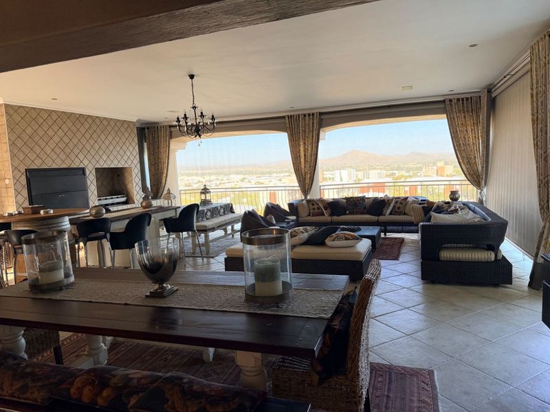Spacious covered balcony featuring a built-in braai, tiled flooring, and expansive views, perfect for outdoor entertaining.
