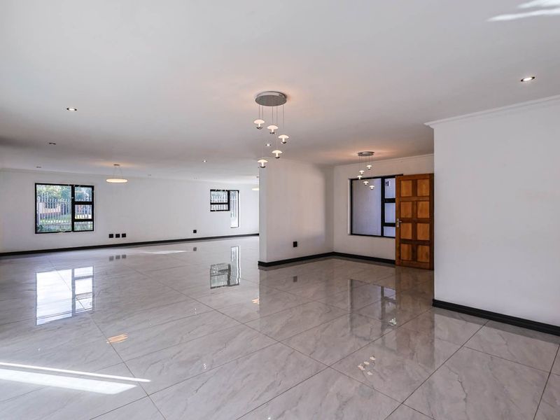 Spacious open-plan living area featuring polished porcelain floor tiles, modern pendant lighting, and large windows providing ample natural light.