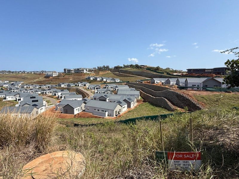 An elevated view of a residential estate development featuring multiple homes and retaining walls, with a vacant land plot for sale in the foreground.
