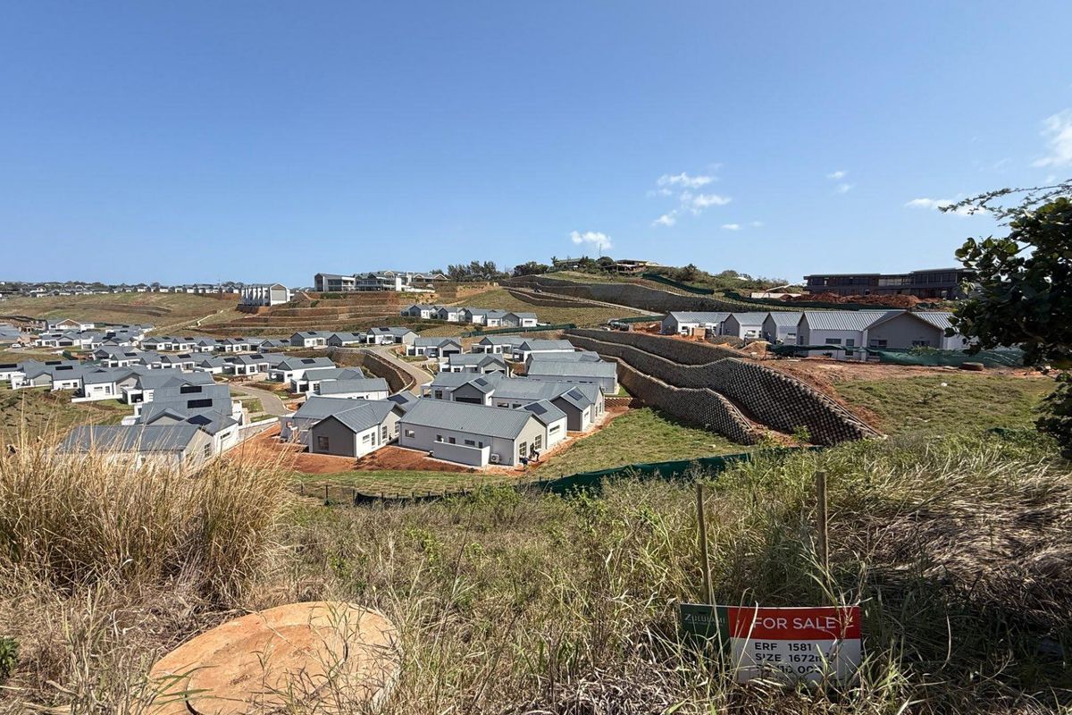 An elevated view of a residential estate development featuring multiple homes and retaining walls, with a vacant land plot for sale in the foreground.