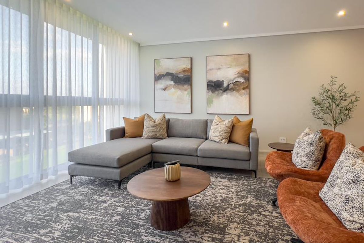 A bright and modern living room featuring floor-to-ceiling windows with sheer curtains and recessed downlighting.