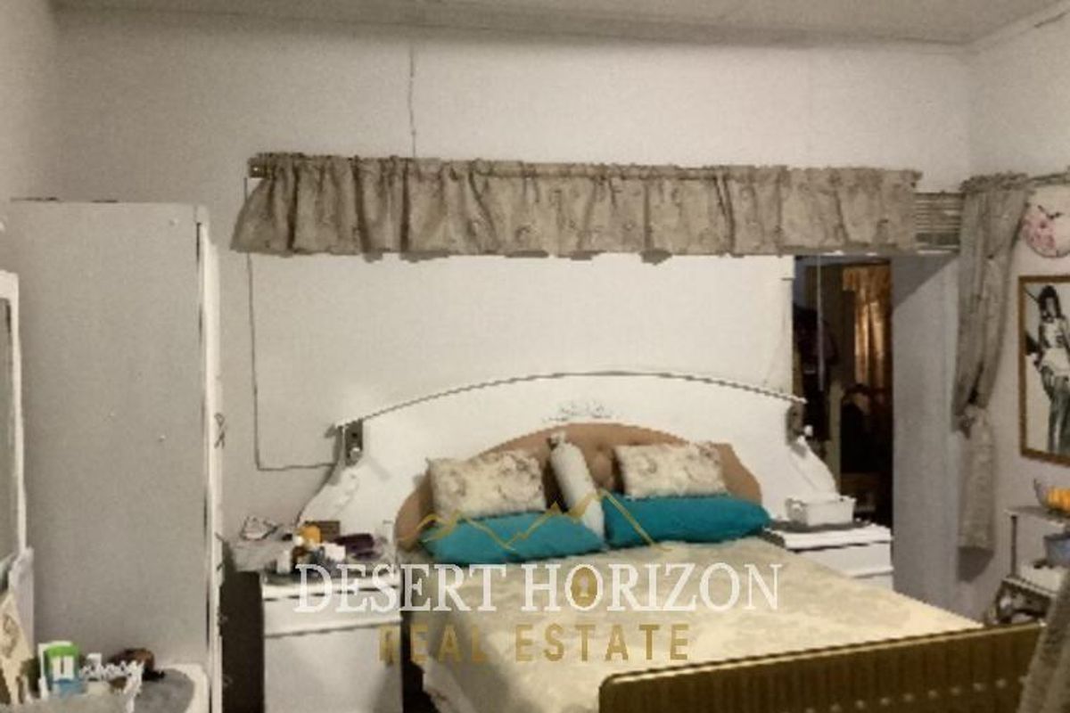 A bedroom featuring tiled flooring and a simple ceiling, showing signs of wear and requiring cosmetic updates.