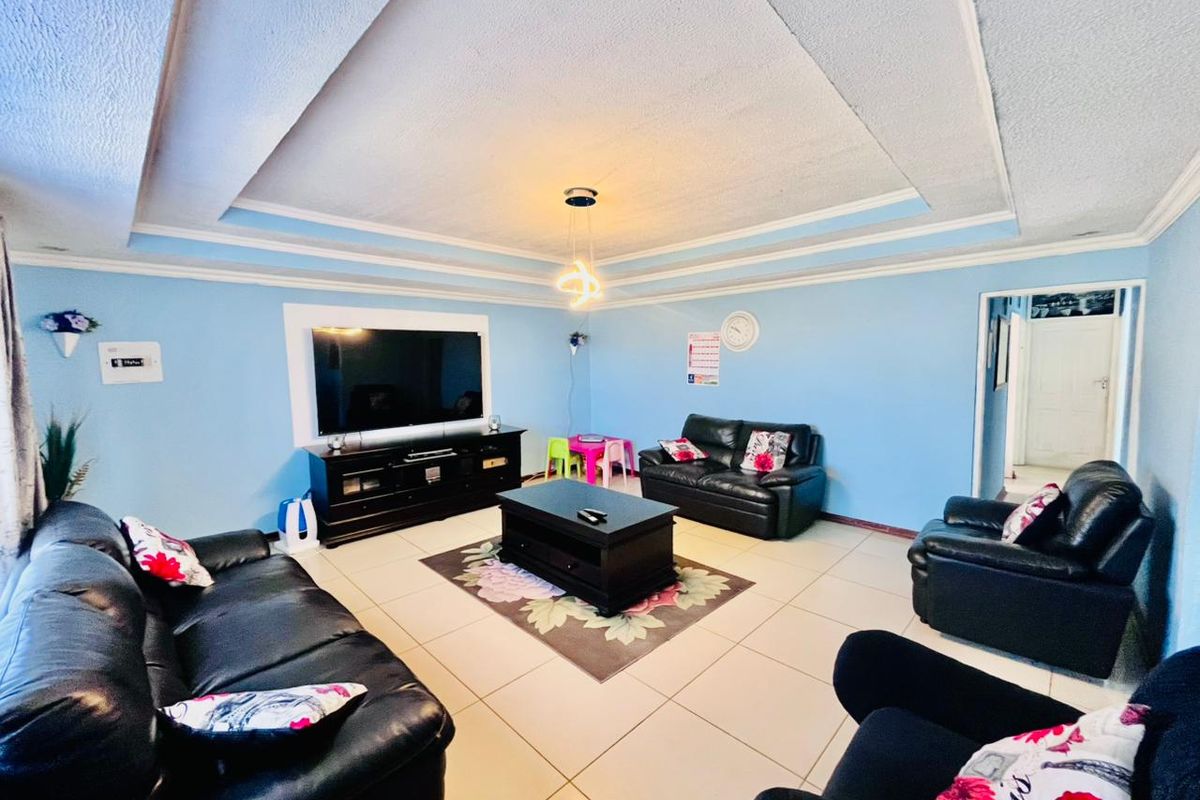 Spacious living room featuring a recessed tray ceiling with integrated lighting and neutral floor tiling.