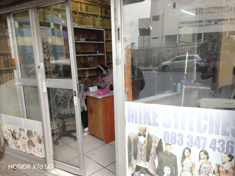 Small retail shop entrance featuring glass storefront doors, tiled flooring, and built-in shelving units suitable for a service-based business.
