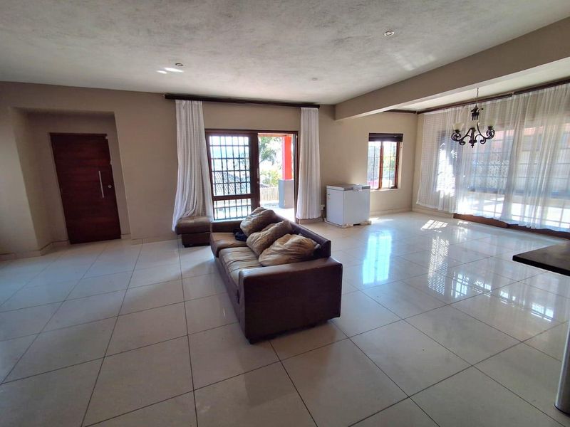 Spacious living area featuring large format floor tiles, recessed lighting, and direct access to an outdoor patio through sliding glass doors.