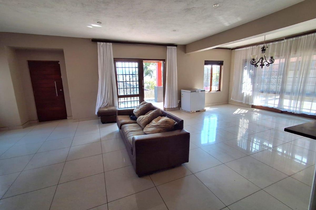 Spacious living area featuring large format floor tiles, recessed lighting, and direct access to an outdoor patio through sliding glass doors.