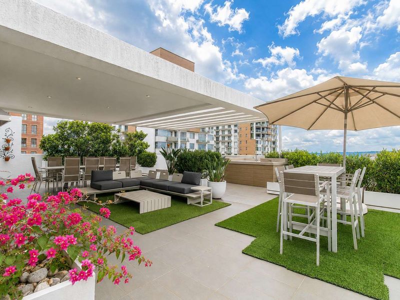 Spacious penthouse terrace featuring a covered patio area, tiled flooring, built-in planters, and integrated lighting, perfect for outdoor entertaining.