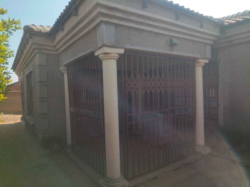 Front exterior view of the house featuring concrete columns and security gate protection.